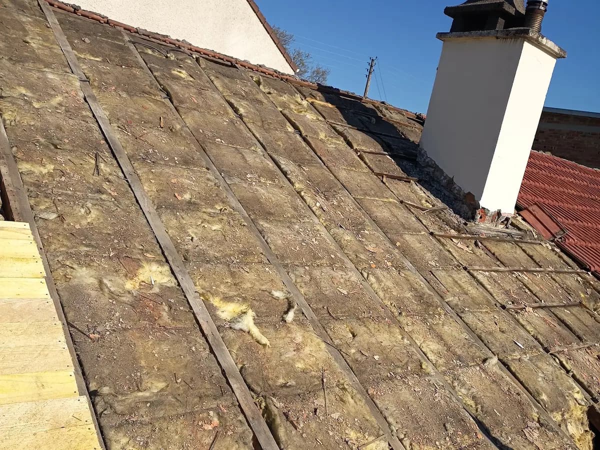 Toiture entièrement déposée : voliges anciennes, ancien isolant tassé entre chevrons, voligeage neuf commencé sur la gauche