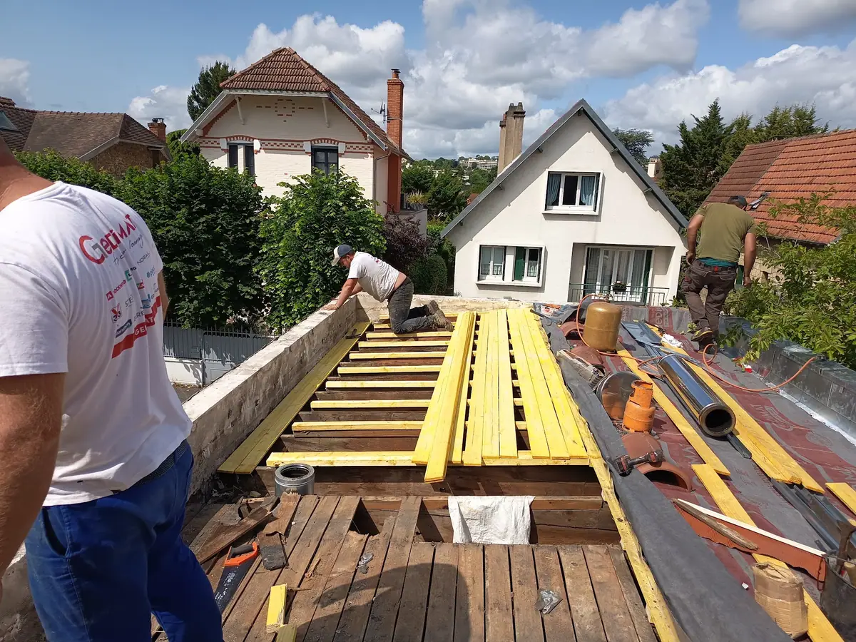 Équipe de couvreurs posant un voligeage neuf sur la charpente d'une toiture déposée — chantier ETS Louis Père et Fils